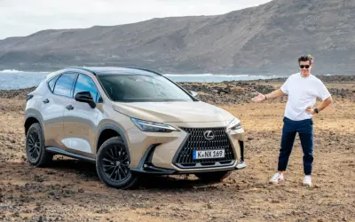 Mężczyzna prezentuje jeden z najnowszych lexus suv modele na tle surowego krajobrazu z morzem i górami.