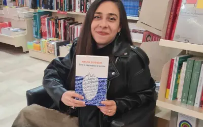 Una giovane donna sorride in libreria, tenendo in mano il libro "Dove si nascondono le lacrime".