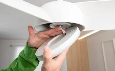 Manos conectando cables para como instalar un ventilador de techo con luz.
