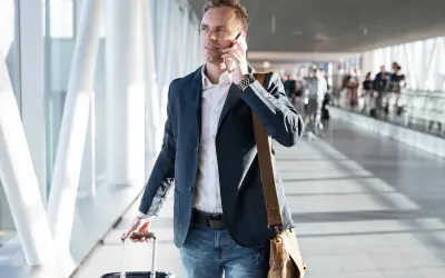 Mężczyzna w marynarce rozmawia przez telefon, ciągnąc walizkę. Może to być związane z podróżą służbową, o której mowa w art. 21 ust. 1 pkt 152 ustawy o podatku dochodowym.