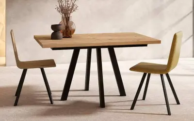 Mesa comedor extensible de madera con patas metálicas negras, ideal para ampliar el espacio. Dos sillas modernas flanquean la mesa.