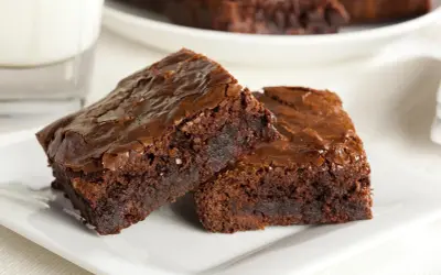 Dwa wilgotne brownie z nutellą, posypane solą morską, na białym talerzyku.