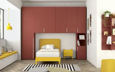 Soluzione moderna per organizzare armadio a ponte bambini: letto giallo, contenitori a muro rossi e seduta imbottita.
