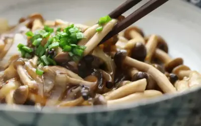 Chopsticks podnoszą pyszne, duszony chińskie grzyby, posypane zieloną cebulką.