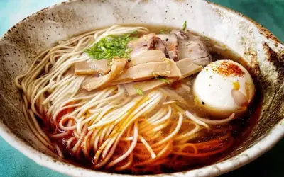 Miseczka zupy ramen z makaronem, jajkiem na twardo, plastrami mięsa i bambusem. Idealny zupa ramen przepis oryginalny.