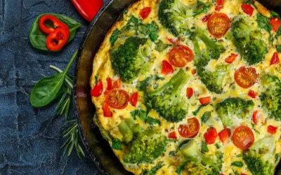 Pyszny omlet z warzywami: brokuły, pomidorki koktajlowe i papryka w złocistym jajku. Idealny na śniadanie.