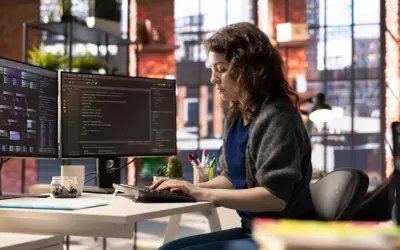 Une développeuse code sur deux écrans, explorant a quoi sert Java pour créer des applications complexes.