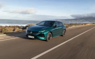 Zielony Peugeot 308 jedzie wzdłuż malowniczego wybrzeża.