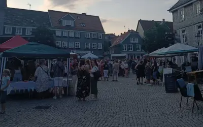 Menschen genießen den Abend auf dem Markt Remscheid. Stände mit Zelten und Tische unter Sonnenschirmen laden zum Verweilen ein.