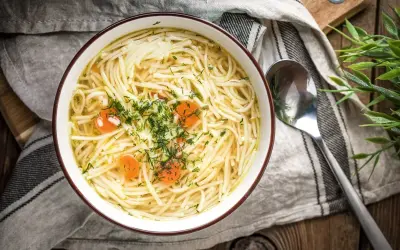 Miseczka aromatycznego rosołu z makaronem i marchewką, posypana koperkiem. Idealny, gdy szukasz czegoś lekkiego i niskokalorycznego - rosół kcal.