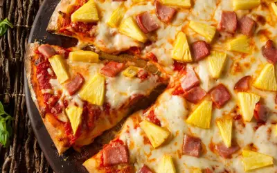 Pizza hawajska z kawałkami ananasa i szynki na roztopionym serze.