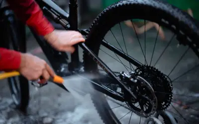 Iemand maakt de fietsketting schoon met Dasty, terwijl de rest van de fiets nat wordt gespoten.