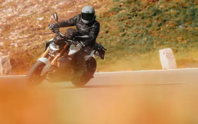 Motociclista con casco y chaqueta de cuero en una moto deportiva, disfrutando de la carretera. Ideal para quienes buscan el permiso conducir A1.