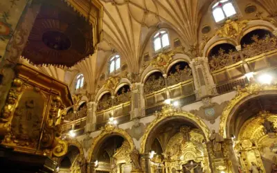 Interior del real seminario de San Carlos, con altares dorados, arcos ornamentados y techos abovedados.