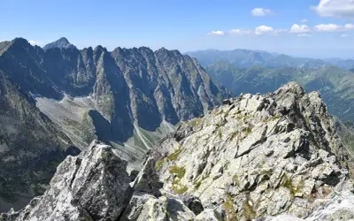 Kamienista grań na trasie na Koprowy Wierch. Majestatyczne szczyty Tatr Wysokich w tle.