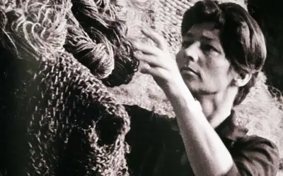 Magdalena Abakanowicz z dłońmi wśród swoich monumentalnych, plecionych dzieł, abakanów.
