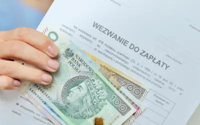 Dłoń trzyma banknoty 100 i 200 zł na wezwaniu do zapłaty. Zastanawiasz się, ile zarabia komornik?