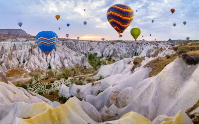 Balony unoszą się nad Kapadocją, tworząc malowniczy widok. To idealne miejsce na wakacje, gdzie można podziwiać piękno natury i poczuć się jak po szczepieniach na nudę w Turcji.