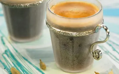 Dwie filiżanki kawy z pianką, obok strączki kardamonu. Zastanawiasz się, ile kardamonu do kawy dodać, by uzyskać ten aromat?
