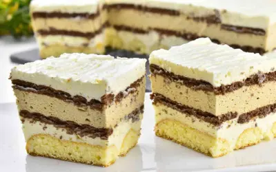 Pyszne ciasto caffe latte z warstwami biszkoptu, kremu kawowego i czekolady, zwieńczone bitą śmietaną.