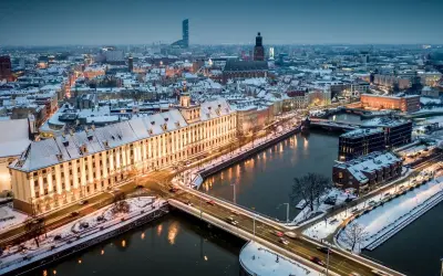 Zimowy Wrocław nocą. Ośnieżone dachy, rzeka i mosty tworzą magiczny widok. Warto odkrywać wrocławskie atrakcje zimą.