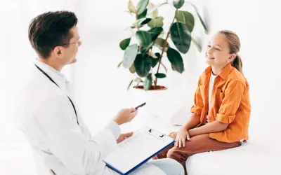 Lekarz rozmawia z uśmiechniętą dziewczynką o jej ADHD. Leczenie może przynieść ulgę i poprawić jakość życia.