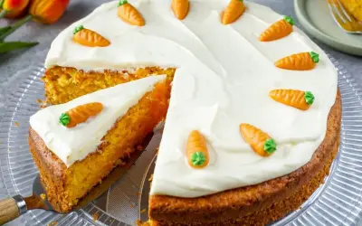 Ein saftiger Karottenkuchen mit weißem Zuckerguss und kleinen Marzipanmöhren, perfekt als Geburtstagskuchen für Kinder.