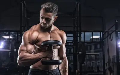 Uomo muscoloso in palestra con manubrio, focus sulla definizione muscolare, integrando la creatina per massimizzare i risultati.