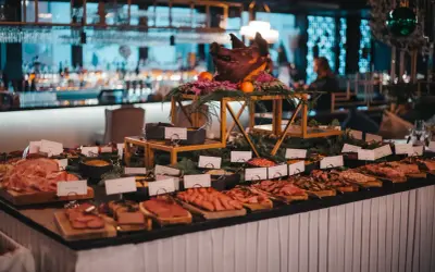Ett dignande julbord med charkuterier, en dekorerad grisbuk och en bar i bakgrunden. En festlig Mister French julbord-upplevelse.