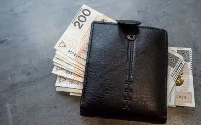 Czarny portfel z polskimi banknotami. Zastanawiasz się, jak obliczyć chorobowe w ciąży? Finanse przyszłej mamy.