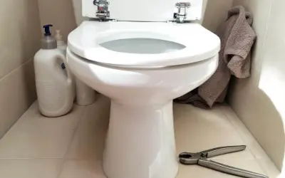 Préparez-vous à changer l'abattant WC. Nettoyants, serviette et pince à portée de main pour le bricolage.