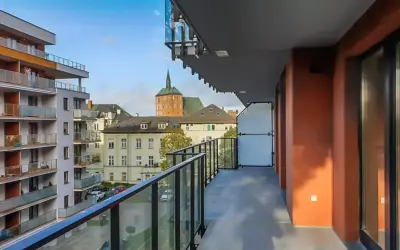 Widok z balkonu na nowoczesne bloki i zabytkowe kamienice w Kołobrzegu. Pilnie sprzedam mieszkanie w tej okolicy!