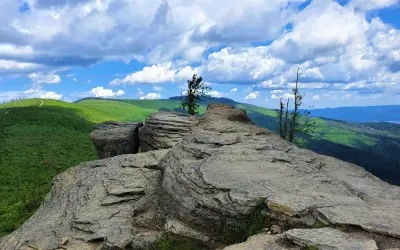 Skrzyczne szlaki wiodą przez skaliste szczyty i zielone wzgórza. Widok zapiera dech w piersiach, a chmury na niebie dodają dramatyzmu.