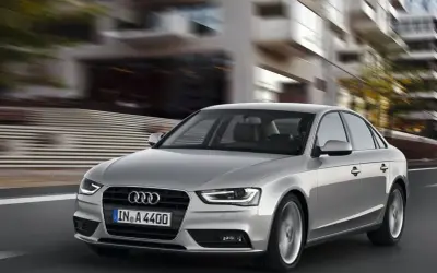 Srebrne Audi A4 B8 w ruchu miejskim. Typowe usterki tego modelu mogą dotyczyć elektroniki lub układu napędowego, ale ten egzemplarz wygląda bez zarzutu.
