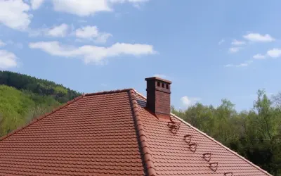 Solidna cegła klinkierowa na komin, dumnie wznosząca się nad czerwonym dachem.