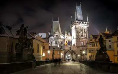 Most Karola w Pradze nocą, ośnieżony, z wieżami i rzeźbami. Idealne miejsce na wycieczki objazdowe po Europie.