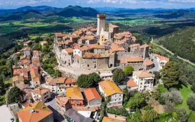 Un borgo medievale con un castello domina le colline toscane. Perfetto per un weekend in Toscana, tra tetti rossi e panorami mozzafiato.