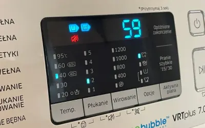 Panel pralki z ikonami i cyfrowym wyświetlaczem. Widoczny symbol prania wstępnego, czas 59 minut i opcje wirowania.