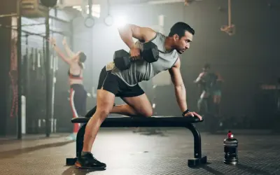 Mann trainiert im Fitnessstudio mit Hanteln. Mit diesem Training macht er fett fett.