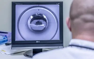 Opis rezonansu magnetycznego głowy. Na ekranie widać wnętrze aparatu MRI, przez które przechodzi pacjent.