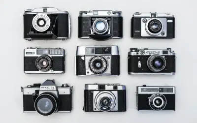 Kolekcja aparatów analogowych, od kompaktowych po bardziej zaawansowane modele, prezentuje historię budowy aparatu cyfrowego.