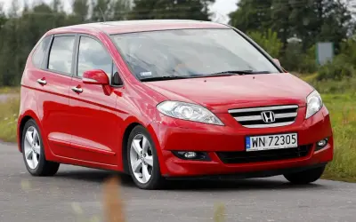 Czerwona Honda FR-V na drodze, z widocznym logo i tablicą rejestracyjną.