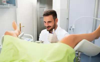 Lekarz ginekolog w gabinecie, wykonuje badanie. Czy do ginekologa na NFZ można iść wszędzie? Tak, można wybrać dowolną placówkę.