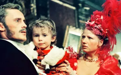 Rodzina w bogatych strojach, ojciec trzyma dziecko. Scena z filmu "Ziemia obiecana" streszczenie.