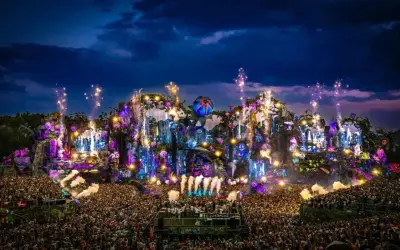 Un'enorme folla festeggia sotto un palco spettacolare, illuminato da luci colorate e fuochi d'artificio. È il luogo dove fanno il Tomorrowland, un'esplosione di musica e magia.