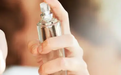 Eine Hand hält einen Glasflakon, bereit, einen selbstgemachten Erfrischungsspray aufzusprühen.
