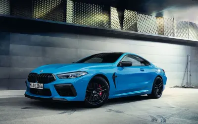 Niebieskie BMW M8 Coupe na tle nowoczesnej architektury.