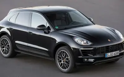 Czarny Porsche Macan na ciemnym tle. Choć piękny, warto znać jego potencjalne wady przed zakupem.