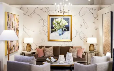A living room with traditional interior design, featuring a floral wallpaper, a painting of tulips, a brown sofa, and plush armchairs.