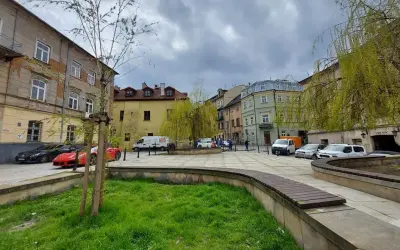 Plac rybny Lublin z kolorowymi kamienicami, zielenią i zaparkowanymi samochodami.